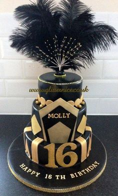 a black and gold birthday cake with an ostrich feather decoration on the top