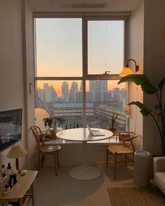 a living room filled with furniture and a large window overlooking a cityscape in the distance