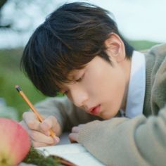 a young boy writing on a piece of paper with an apple in front of him