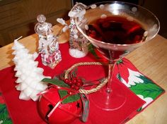 a glass of wine sitting on top of a red place mat next to christmas decorations