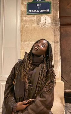 a woman with dreadlocks standing in front of a sign that says rue cardinalal lemonne