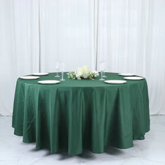 a green table cloth with white plates on it