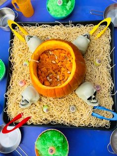 a table with halloween decorations and pumpkins on it, including an orange bowl filled with rice