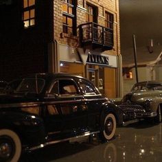 antique cars parked in front of a building at night