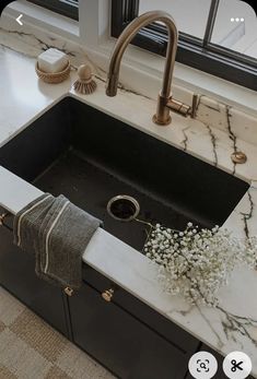 a kitchen sink with marble counter top and gold faucet