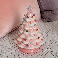 a pink ceramic christmas tree sitting on top of a bed