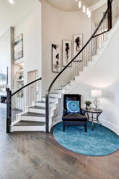 a living room filled with furniture and a stair case next to a blue rug on top of a hard wood floor