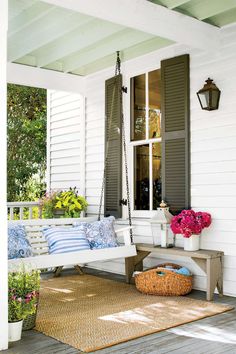 a porch swing with pillows and flowers on it