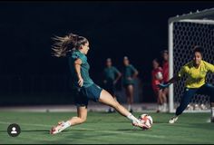 two women playing soccer on a field at night