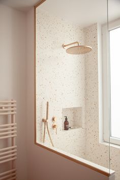 a bathroom with a shower head and hand held shower faucet next to a window