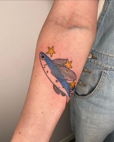 a person with a small tattoo on their arm that has a fish and stars on it