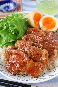 a plate with meat, rice and orange slices on it next to an egg in the background