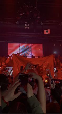 people holding up cell phones in front of a large screen with an eagle on it