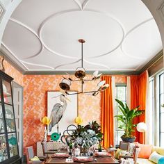 a dining room with orange walls and an ornate chandelier hanging from the ceiling