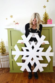 a woman standing in front of a green cabinet holding a snowflake cutout