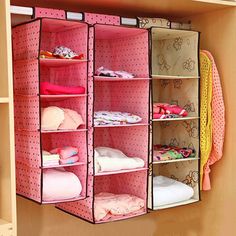 an open closet with clothes hanging on the wall and pink polka doted fabric in it