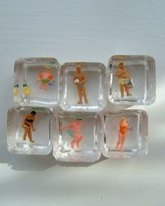 six small plastic figurines sitting on top of each other in glass trays