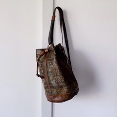 Discover this unique, handmade vintage leather backpack, crafted from soft, high-quality Moroccan leather. Featuring an intricate, abstract ethnic pattern, this bucket-style bag is both stylish and functional. The bag's natural patina, developed over time, adds a touch of vintage charm. The soft, supple leather is dyed with natural colors, creating a stunning palette of browns and greens. Key Features: Handmade in Morocco: Crafted with care and attention to detail. High-Quality Leather: Durable Artisan Bucket Bags For Travel, Artisan Bucket Travel Bag, Brown Bucket Backpack For Daily Use, Traditional Brown Hobo Bag With Adjustable Strap, Artisan Bucket Shoulder Bag For Daily Use, Brown Bucket Bag With Adjustable Strap For Festival, Traditional Bucket Bag With Adjustable Strap For Everyday, Artisan Bucket Bag With Adjustable Strap For Travel, Artisan Travel Bucket Bag With Adjustable Strap