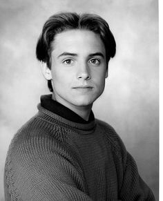 an old black and white photo of a man in a sweater looking at the camera