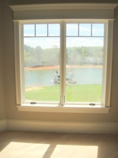 an empty room with two windows overlooking a lake