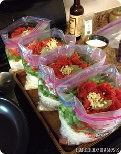 several bags of food sitting on top of a wooden tray next to a wine bottle