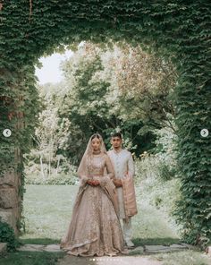 a bride and groom standing under an archway