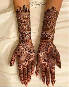 two hands with henna designs on them, one is showing off the intricate design