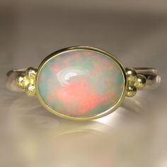 Beautiful, natural, solid Ethiopian opal cabochon set in solid 18k gold bezel on hammered sterling silver band(approx. 26mm wide X 1.5mm thick - hammered from comfy oval wire). Fine silver backsheet underneath stone. Classic solid 18k granule clusters on each side of the opal.  The measures approx. 8 X 10mm. All metal is from recycled sources. This ring is a size 7 and I can stretch to a 7 1/4. Photos have been taken up close for detail. Please refer to dimensions. Attractively boxed. Custom rin Radiant Rings, Gold Opal Ring, Space Rings, Opal Solitaire Ring, Boulder Opal Ring, White Opal Ring, Chic Rings, Opal Band, Ethiopian Opal Ring