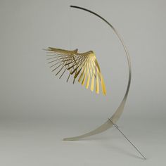 a metal sculpture with a bird on it's back and wings hanging from the top