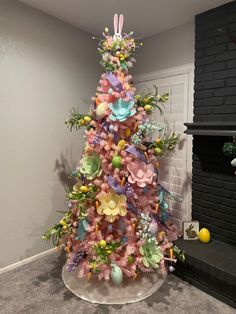 a pink christmas tree decorated with pastel flowers and bunny ears is in front of a fireplace