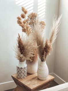 two vases with dried plants in them on a table