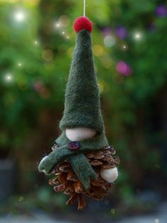 a pine cone ornament with a gnome's hat hanging from the top