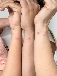 two girls with matching tattoos on their arms, one has a heart tattoo on her arm