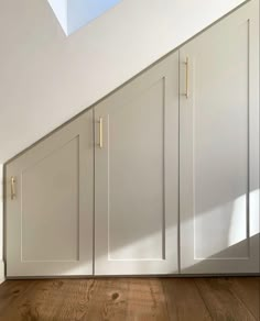 an empty room with white cupboards and wood flooring on the side of it