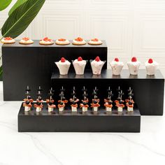 there are many small desserts on the black display stand with red and white toppings