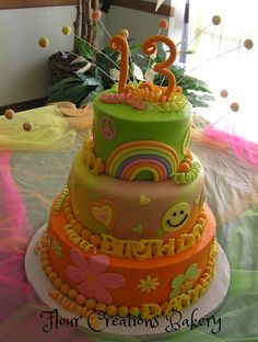 a three tiered birthday cake decorated with rainbows and hearts