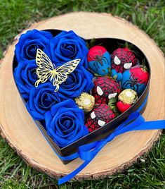 a heart shaped box filled with blue roses and chocolate covered strawberries in the shape of a butterfly