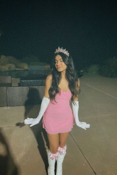 a woman in a pink dress and white gloves posing for the camera with her hands on her hips