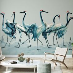 a group of birds standing next to each other in front of a painting on the wall