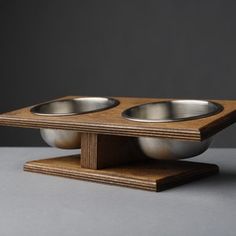 two metal bowls sitting on top of a wooden stand