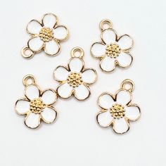 White and light gold colour five petal flower jewelry charms. Perfect focal for  bracelet, necklace, keychain, zipper pulls and other crafting projects.     Made out of Alloy  and Enamel     Light Gold / White Colour Dimensions     about 16x13x3mm, hole 1.8mm Quantity     5 or 10 pieces per pack, choose from dropdown If you need help, please send us a message to assist in any way! Follow us on Facebook for product updates and more great products and services we offer that are not available on Et White Metal Flower Shaped Jewelry, White Metal Flower-shaped Jewelry, White Metal Jewelry With Flower Charm, White Jewelry With Flower Charm And Shape, Personalized White Metal Charms, White Pendant Charms For Gifts, White Pendant Charms For Gift, White Metal Jewelry With Charms, Gold Flower Charm Pendant