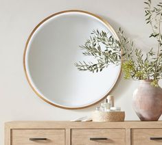 a round mirror sitting on top of a wooden dresser