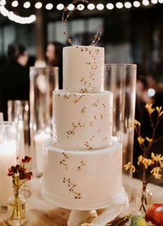 a three tiered cake sitting on top of a table next to candles and flowers