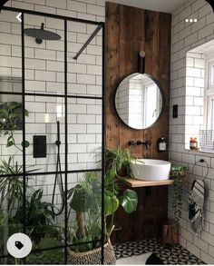 a bathroom with black and white tiled walls, a round mirror over the bathtub