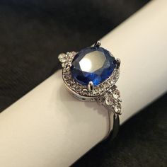 Dazzling Blue Oval Diamond Ring, Cubic Zirconia Sapphire Ring, Oval Blue Sapphire Ring With Diamond Accents, Dazzling Oval Rings For Party, Elegant Blue Crystal Ring For Anniversary, Elegant Blue Crystal Anniversary Ring, Elegant Blue Oval Crystal Ring, Dazzling Oval Sapphire Ring, Sapphire Crystal Ring With Halo Setting For Promise