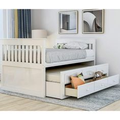 a white bunk bed with drawers underneath it and pictures on the wall behind it in a bedroom