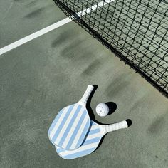 a tennis racquet and ball laying on the ground next to a caged in area