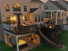 an aerial view of a house at night with lights on the deck and fire pit