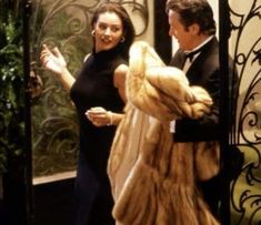 a man and woman are walking out of an elevator together, dressed in furs