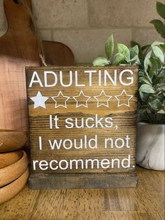 a wooden sign that says adulting it sucks i would not recommend